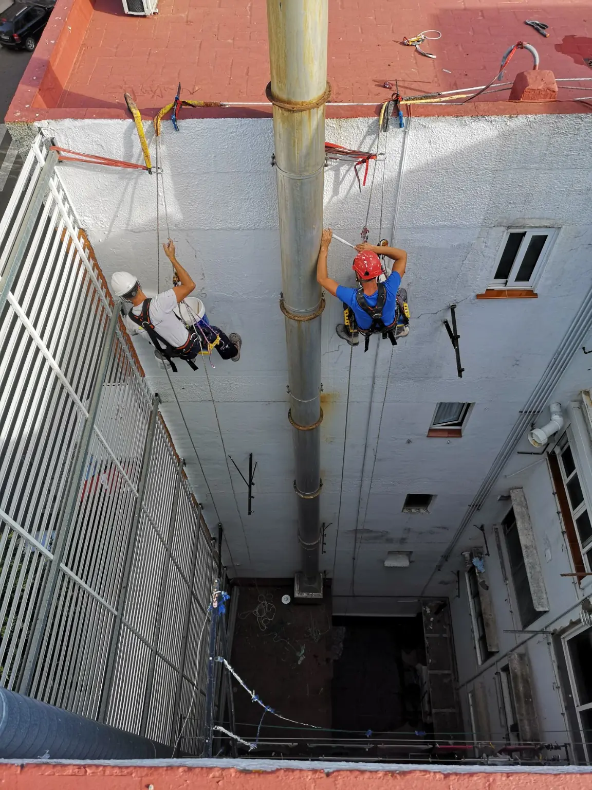 Equipo de Vertical Paint trabajando mediante cuerdas en un patio interior
